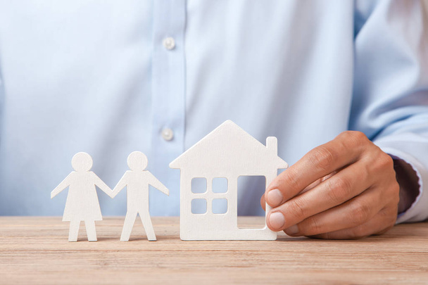 Koncepcji wynajmu domu, kredytu lub ubezpieczenia. Człowiek w koszuli trzyma Dom i rodzina stoi następny  - Zdjęcie, obraz