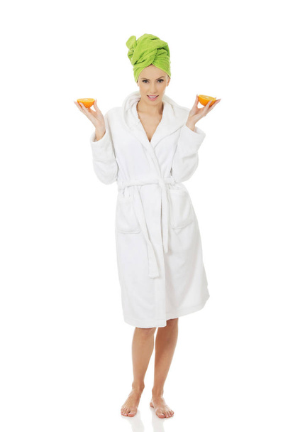 Spa woman in bathrobe holding orange. - Фото, изображение