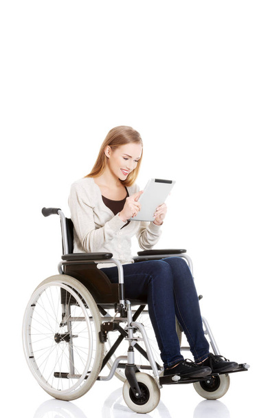 Beautiful casual woman sitting on w wheelchair with tablet. - Valokuva, kuva