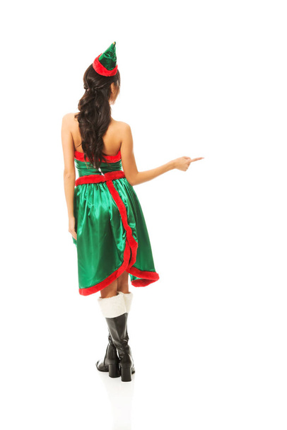 Back view of woman wearing elf clothes pointing to the right - Фото, зображення