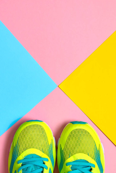 Pair of sport shoes on colorful background. New sneakers on pink, blue and yellow background, copy space. Overhead shot of running shoes. Top view, flat lay - 写真・画像