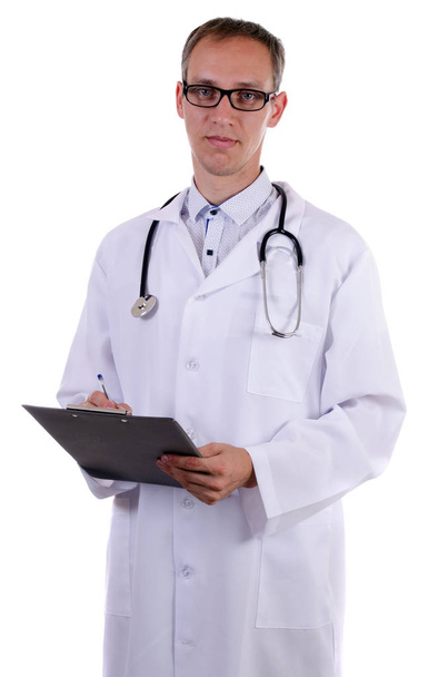 Bir doktor bir stetoskop ve gözlük ile Beyaz paltolu bir klasör izole bir arka plan üzerine yazmak için tutar - Fotoğraf, Görsel