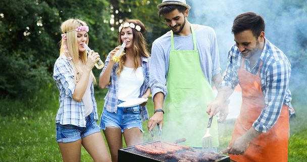 Friends having a barbecue party in nature while having a blast - Foto, imagen