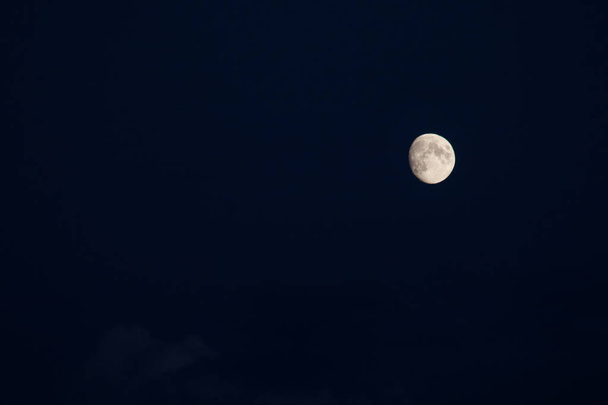 いくつかの目に見える雲と海軍の青空の背景に成長する月の四分の三 - 写真・画像
