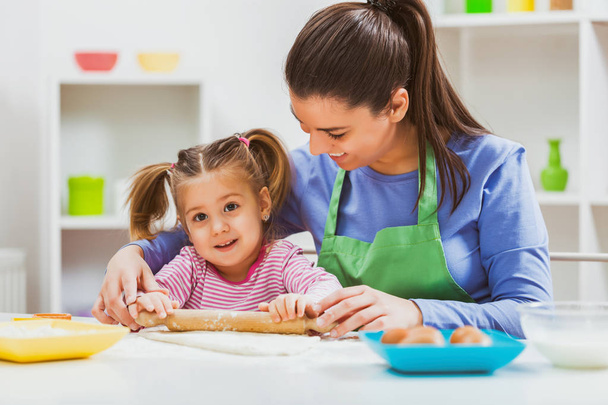 Happy mother and daughter are making cookies in their kitchen.  - Photo, Image