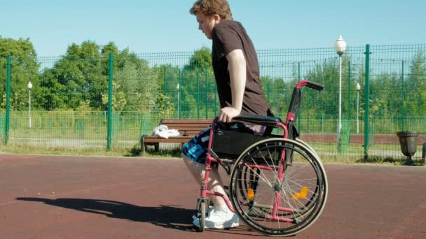 Niepełnosprawny mężczyzna gra koszykówki z wózku, na wolnym powietrzu, podjąć wysiłek podczas odtwarzania - Materiał filmowy, wideo