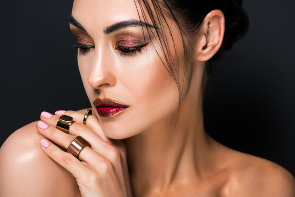 portrait of elegant girl with makeup and golden rings, isolated on black - Fotó, kép