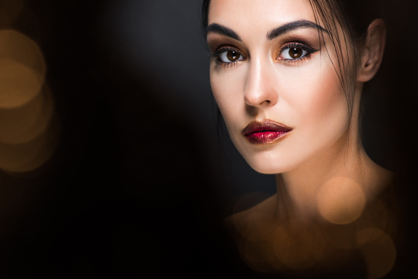 retrato de mujer atractiva con maquillaje posando sobre negro con bokeh dorado
 - Foto, Imagen