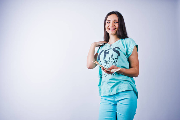Portrait of an attractive girl in blue or turquoise t-shirt and trousers posing with a lot of money in her hand.  - 写真・画像