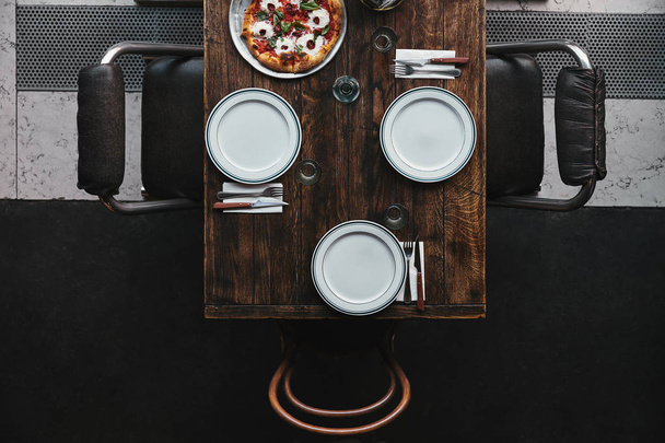 top view of pizza margherita on tray and table setting at restaurant - Фото, изображение
