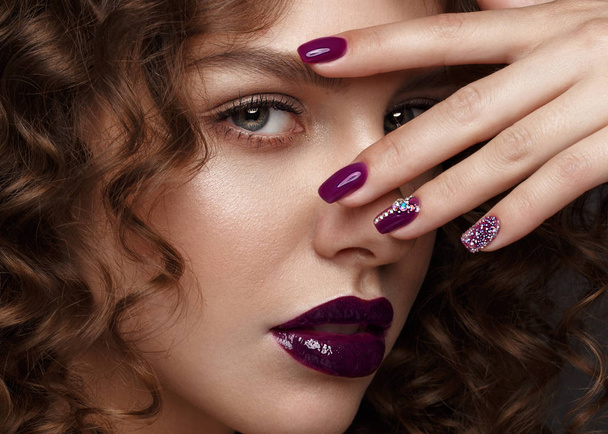 Beautiful girl with evening make-up, purple lips, curls and design manicure nails. beauty face. - Valokuva, kuva