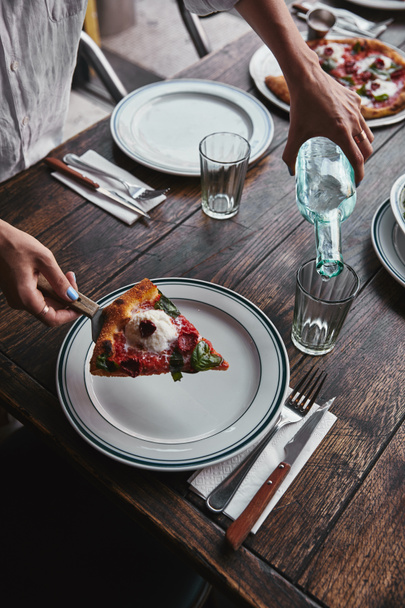 обрезанный снимок женщины, подающей кусочек вкусной пиццы Маргарита на тарелке в ресторане
 - Фото, изображение