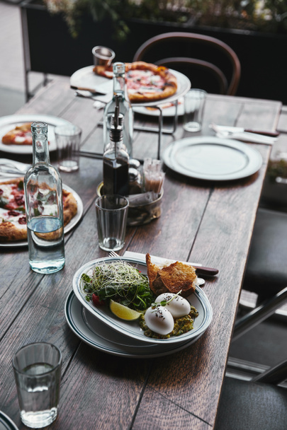 delicious salad and pizza on table at modern restaurant - Φωτογραφία, εικόνα