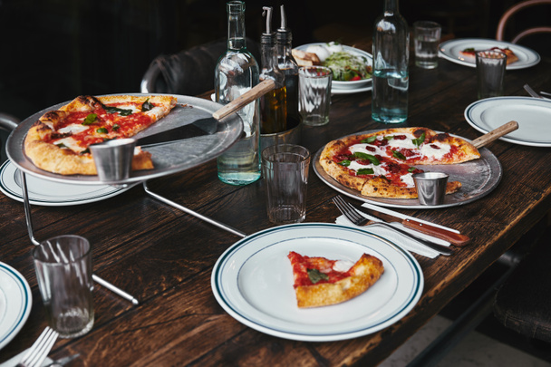 delicious pizza and water on table at modern restaurant - Foto, Imagen