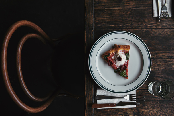 top view of delicious pizza slice on plate with setting and on rustic wooden table - Photo, Image