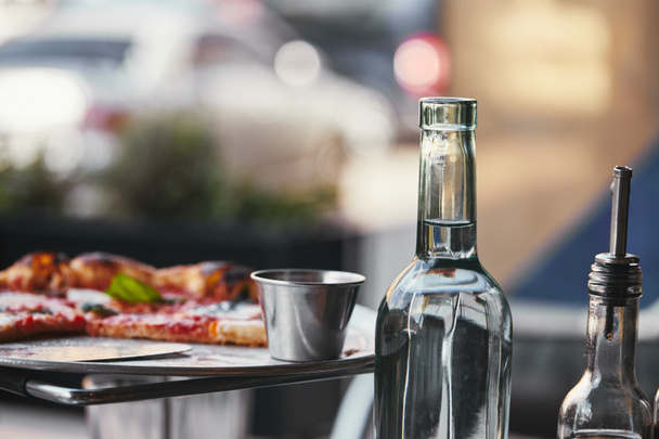 primer plano de deliciosa pizza en bandeja y botella de agua en el restaurante
 - Foto, imagen