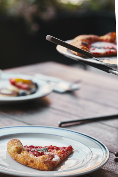 вкусная нарезанная пицца Маргарита на металлическом подносе и тарелке в ресторане
 - Фото, изображение