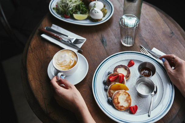 plan recadré de femme avec des crêpes au fromage et café sur une table en bois au restaurant
 - Photo, image