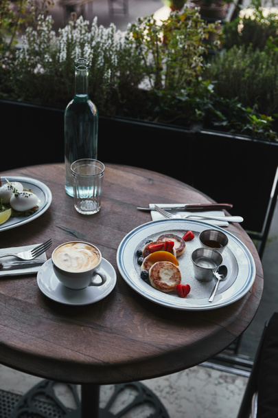 syrniki with coffee and salad on wooden table at restaurant - 写真・画像