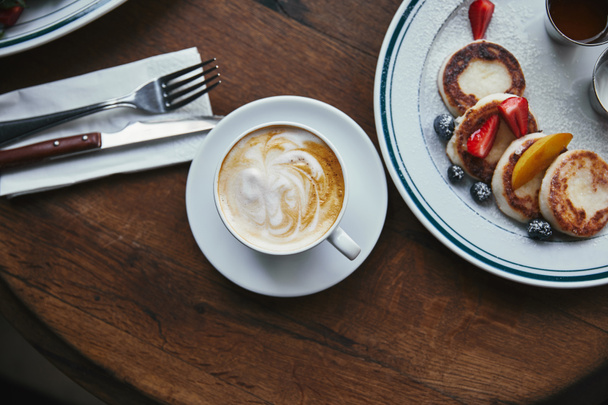 木製のテーブルにコーヒーの果実と syrniki カップのトップ ビュー - 写真・画像