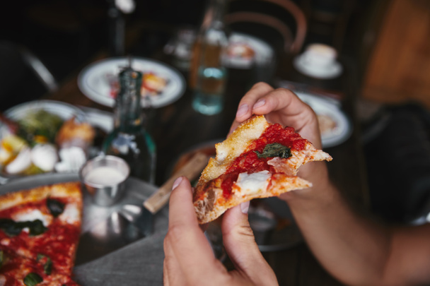 tiro recortado de hombre comiendo pizza recién horneada en el restaurante
 - Foto, imagen