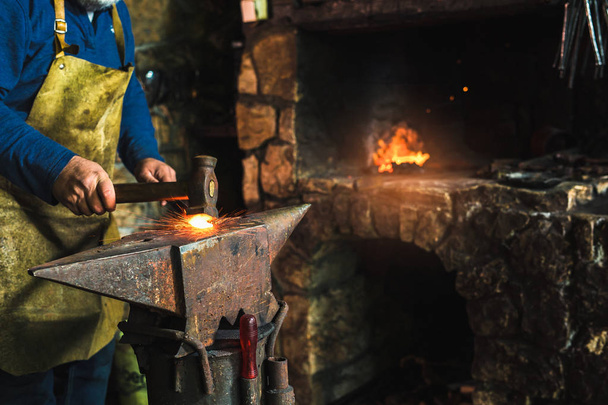 Forge manuelle forgeant du métal fondu sur enclume en forge avec des feux d'artifice, gros plan
 - Photo, image