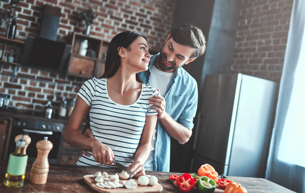 Romantic couple is cooking on kitchen. Handsome man and attractive young woman are having fun together while making salad. Healthy lifestyle concept. - Photo, image