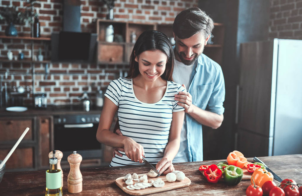 Romantic couple is cooking on kitchen. Handsome man and attractive young woman are having fun together while making salad. Healthy lifestyle concept. - Foto, Imagen