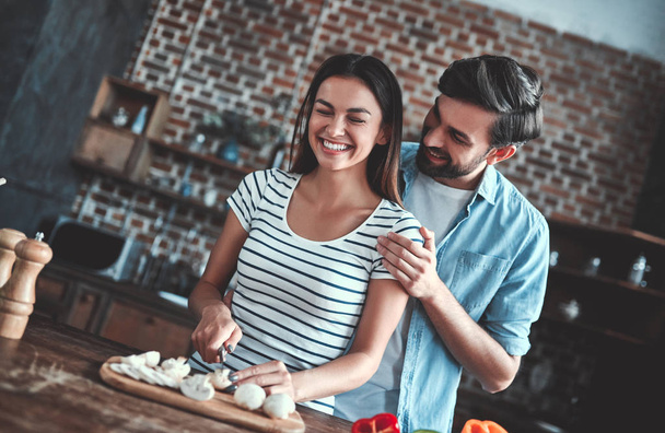 Romantic couple is cooking on kitchen. Handsome man and attractive young woman are having fun together while making salad. Healthy lifestyle concept. - Φωτογραφία, εικόνα