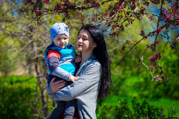 Fiatal anya feltartotta kisgyermek fia karját, családi szórakozás együtt - Fotó, kép