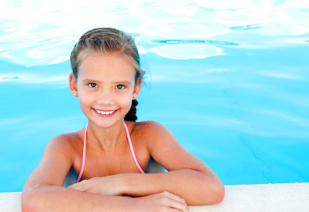 Cute smiling happy little girl child  in swimming pool in summer day - Фото, изображение