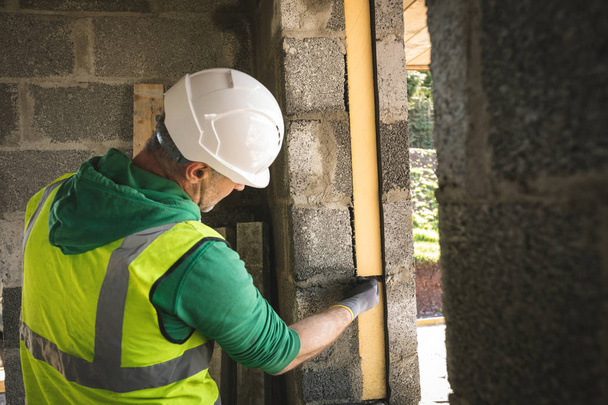 Концентрированный инженер, осматривающий стену на строительной площадке
 - Фото, изображение