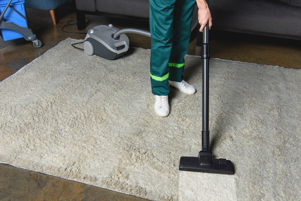 Sicht auf professionelle Reiniger mit Staubsauger und Reinigung des weißen Teppichs - Foto, Bild