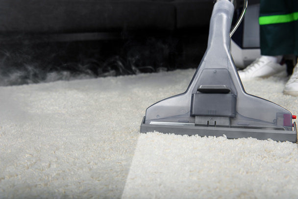 close-up view of person cleaning white carpet with professional vacuum cleaner  - Photo, Image