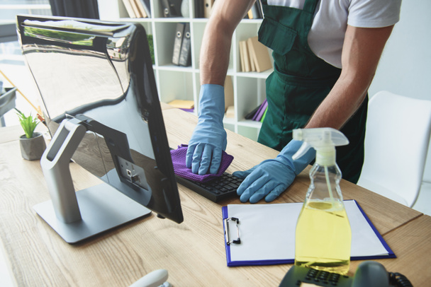 обрізаний знімок професійних чистіше гумові рукавички очищення клавіатура комп'ютера в офісі - Фото, зображення