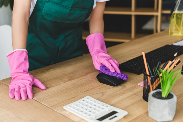 ゴム手袋のオフィスのテーブルの清掃の女性のショットをトリミング - 写真・画像
