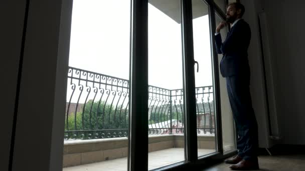Koko kehon liikemies seisoo edessä suuret ikkunat toimistossaan
 - Materiaali, video