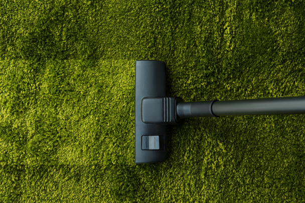 top view of vacuum cleaner cleaning green carpet  - Φωτογραφία, εικόνα