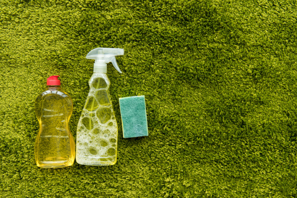 a zöld szőnyeg másol hely palackkal mosó-és tisztítószer és a rag-felülnézet  - Fotó, kép
