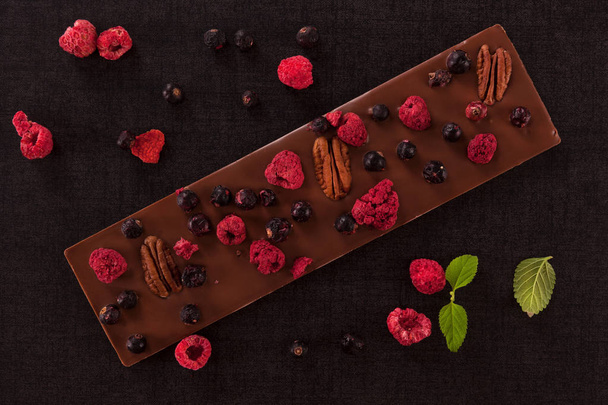 Luxury milk chocolate bar with dry fruit on dark background. Top view. - Photo, Image
