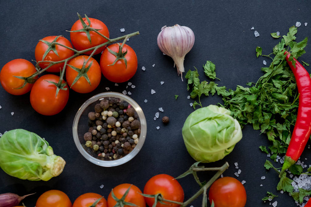 Nahaufnahme von bunten Gewürzen und frischem Gemüse zum Kochen auf dunklem Metallhintergrund mit Platz für Text. Ansicht von oben. Bio gesunde Lebensmittel Zutaten. - Foto, Bild