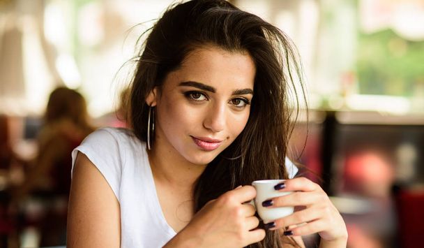 Girl attractive gorgeous brunette middle eastern appearance drinks coffee close up. Woman smiling face make up holds coffee cup. Coffee worldwide traditional drink. Girl enjoy aromatic coffee drink - Foto, Bild