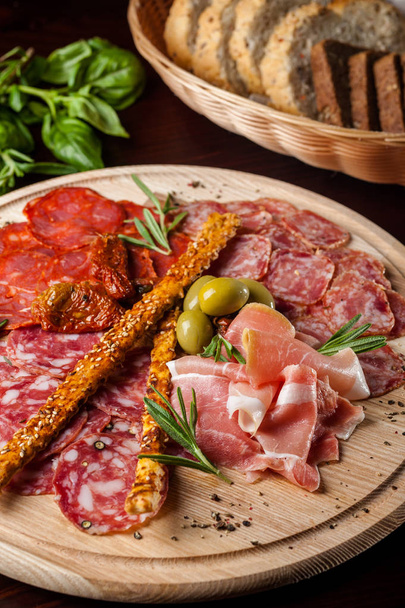 meat sliced proshto, salami, olives and pepper paprika on a wooden plate - Фото, изображение