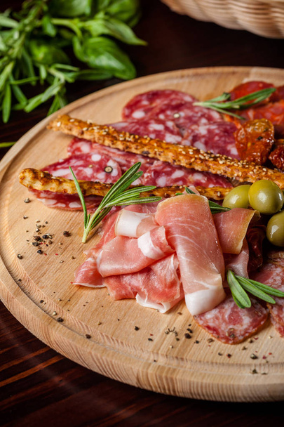 viande tranchée proshto, salami, olives et paprika au poivre sur une assiette en bois
 - Photo, image