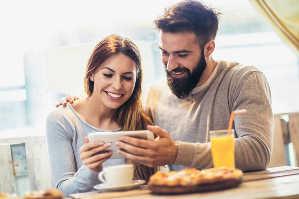 Χαμογελαστά ζευγάρι απολαμβάνει στην πίτσα και χρήση tablet pc σε καφετέρια   - Φωτογραφία, εικόνα