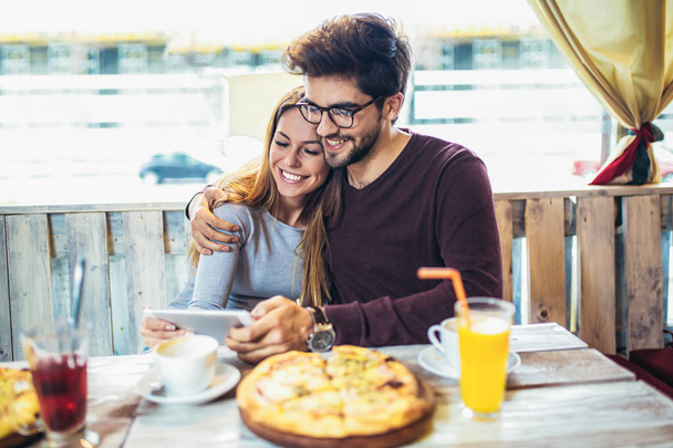 笑顔のカップルのピザを楽しんでしてタブレット pc カフェで   - 写真・画像