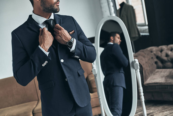 handsome macho man in suit standing at mirror in atelier - Photo, image