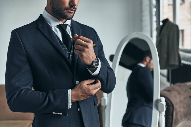 handsome macho man in suit adjusting jacket sleeve in atelier - 写真・画像