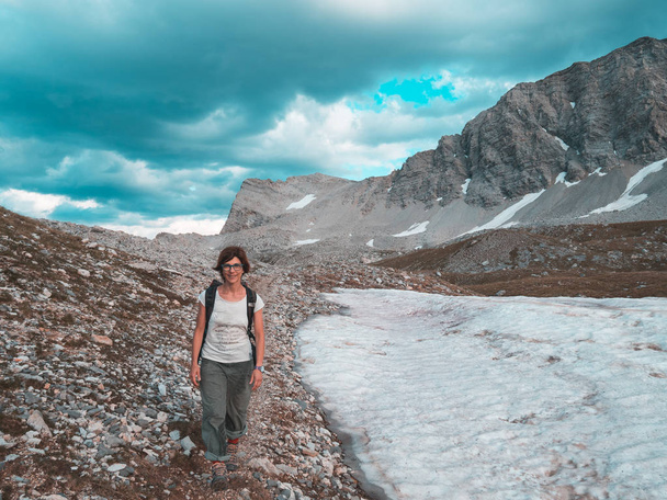 Жінка Backpacker походи в ідилічним пейзажем, Скелястих гір, снігу, драматичні небо. Пригод літніх і розвідку на Альпи. Тоноване. - Фото, зображення