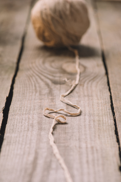 Selektywny fokus untangled beżowy sweter przędzy ball, na podłoże drewniane  - Zdjęcie, obraz